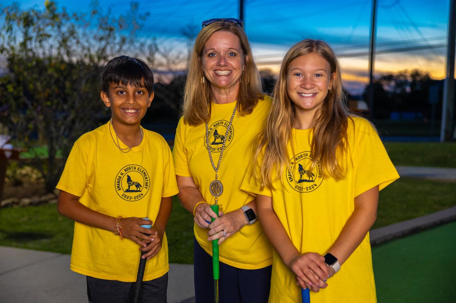 principal with two students at mini golf course